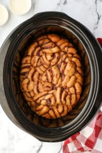 A slow cooker with cinnamon roll pieces baked into a casserole.