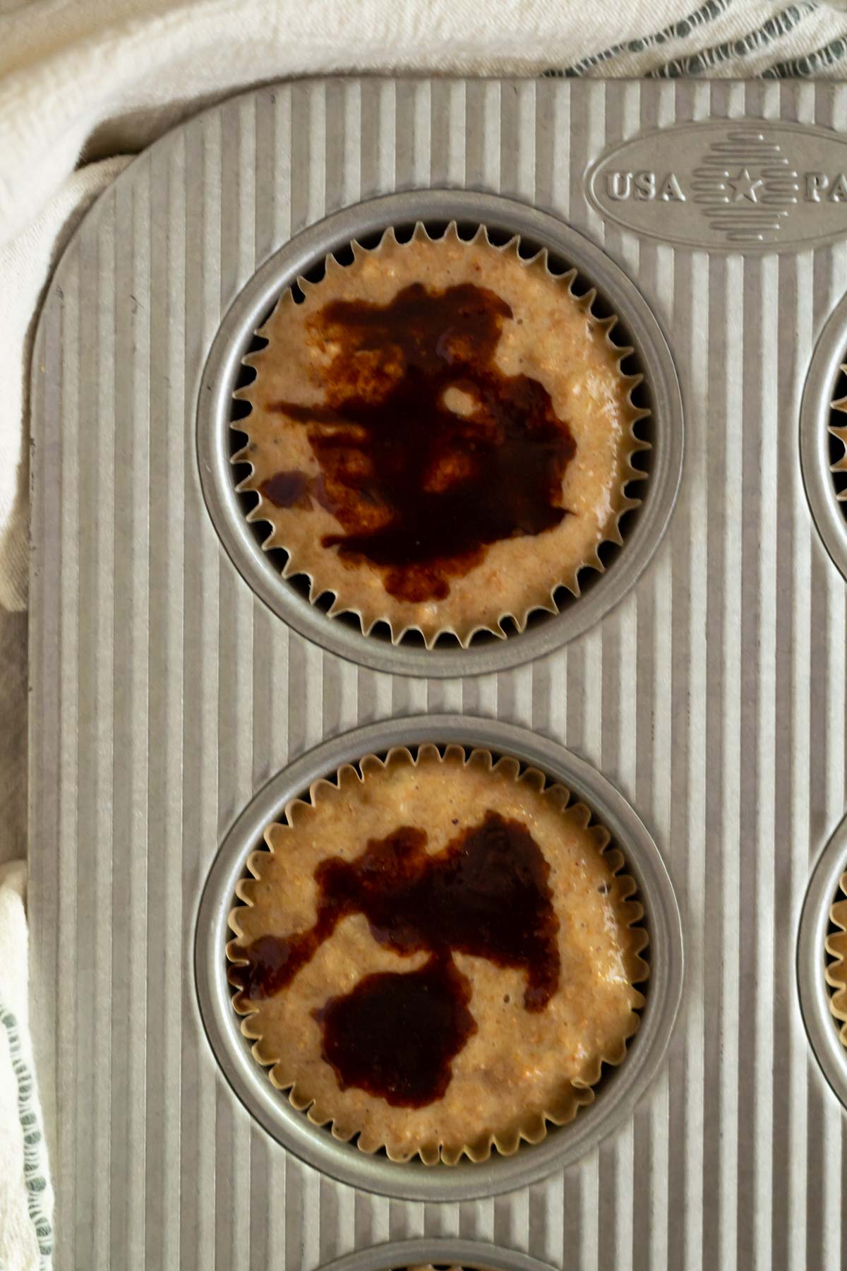 cinnamon sugar on top of muffin batter in a muffin tin