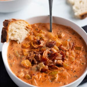 A bowl with homemade salmon chowder with a piece of sourdough bread.