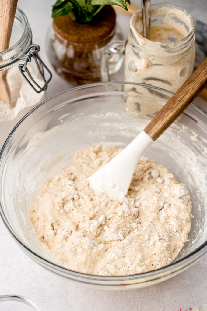 A bowl of sourdough cinnamon roll dough coming together in a bowl with a spatula.