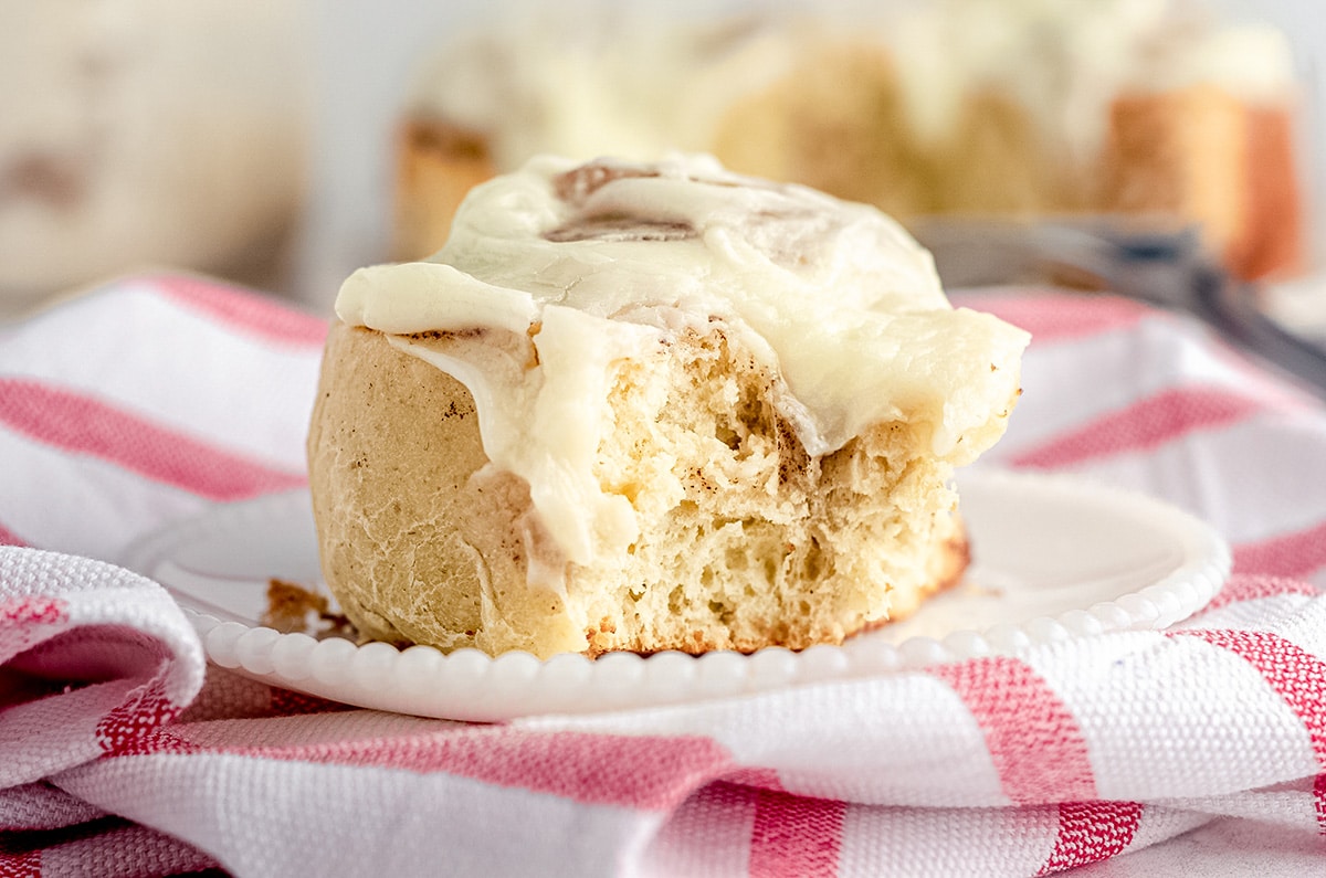 a sourdough cinnamon roll on a plate with a bite taken out of it