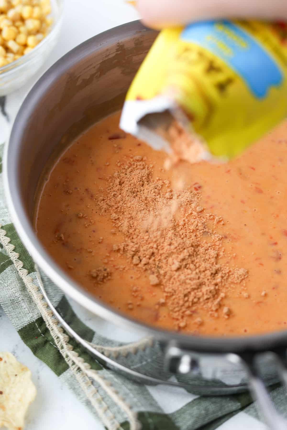 Sprinkling taco seasoning into Rotel dip.