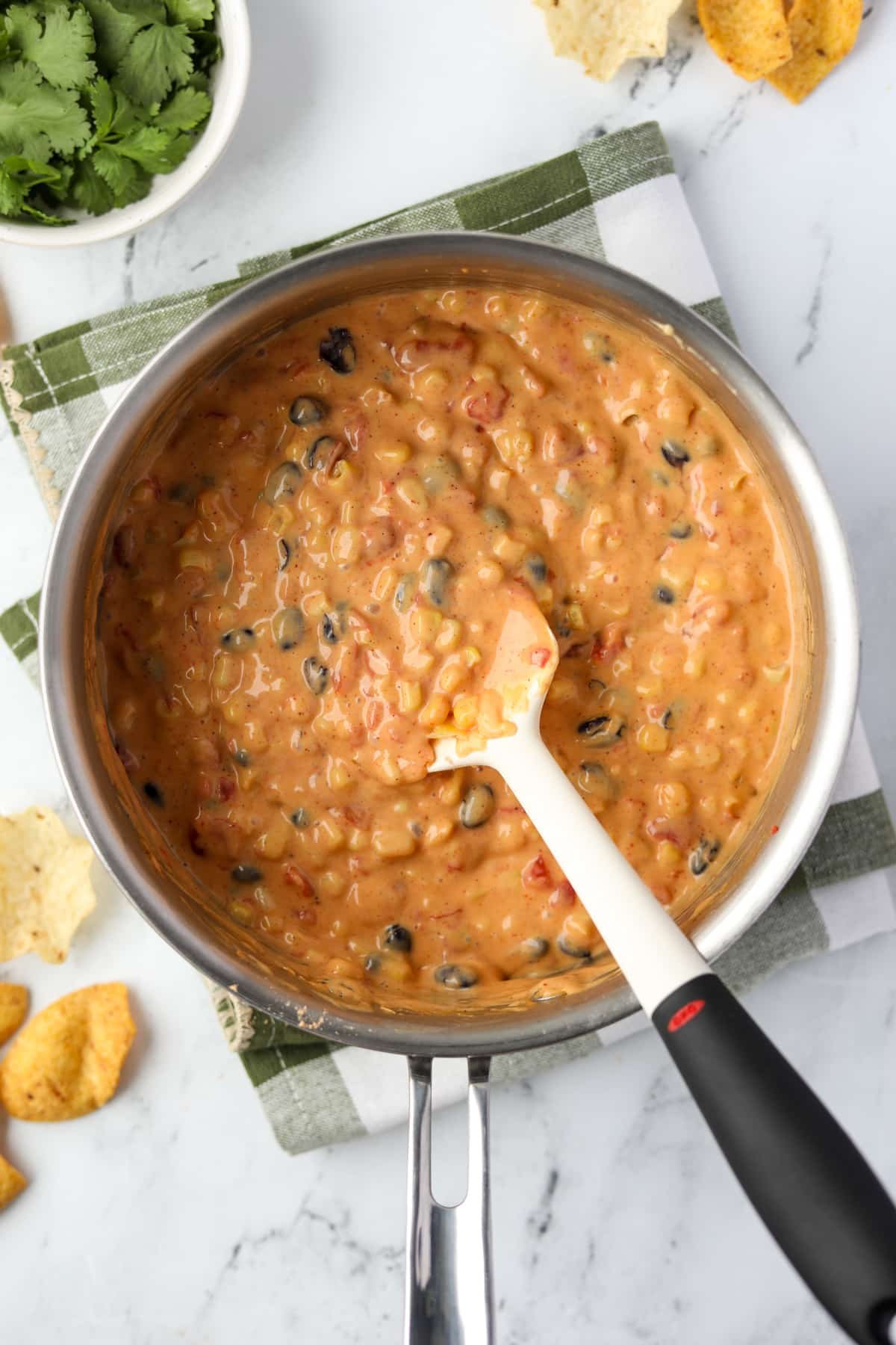 Stirring together velveeta, Rotel, corn, and beans.