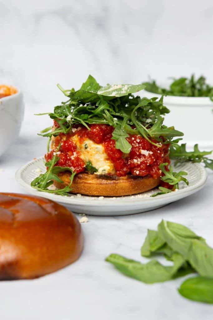 adding fresh arugula salad and parmesan on top of the burgers
