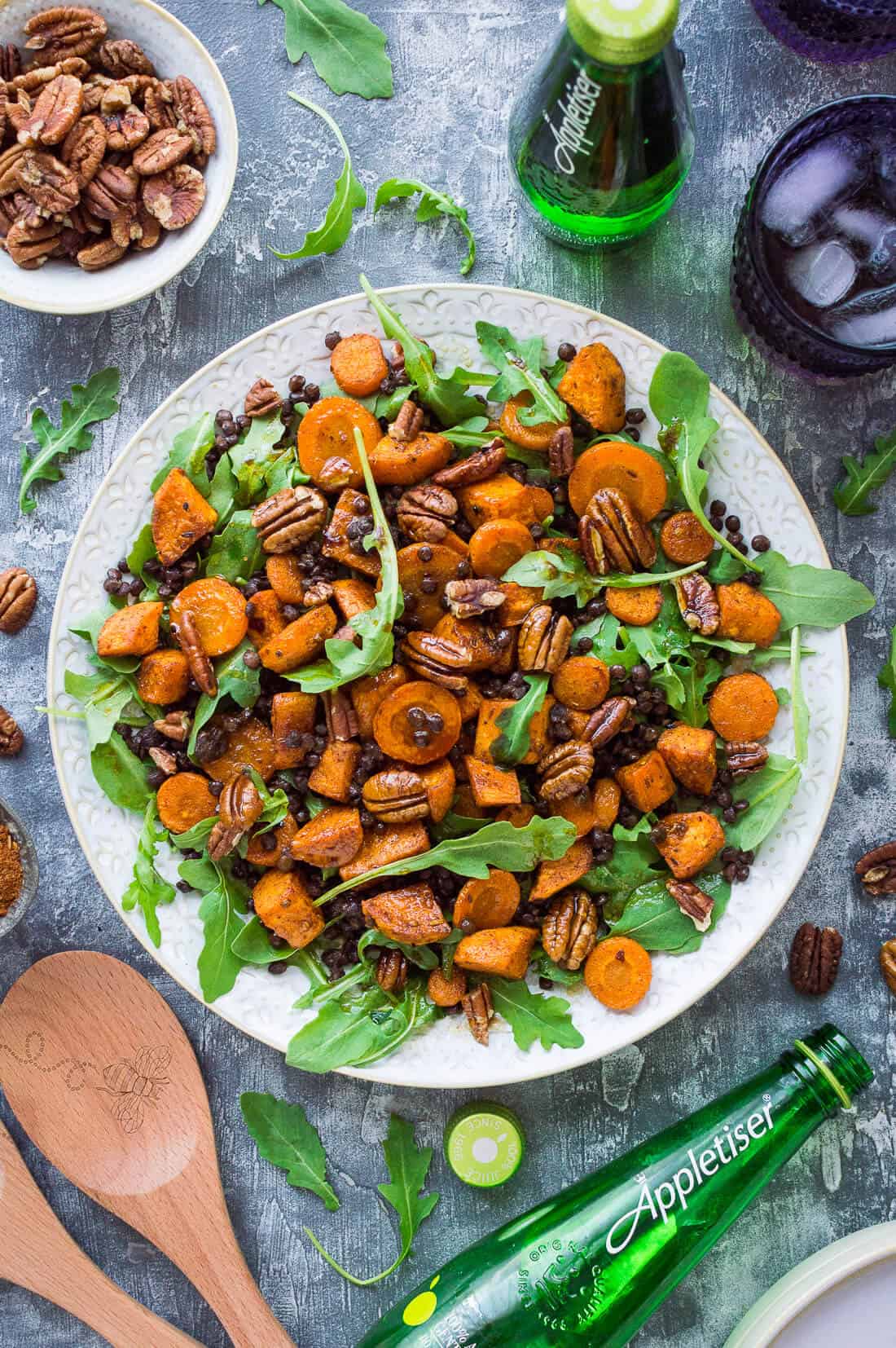 A white platter of roast sweet potato, puy lentil, rocket (arugula) and pecan salad with Appletiser