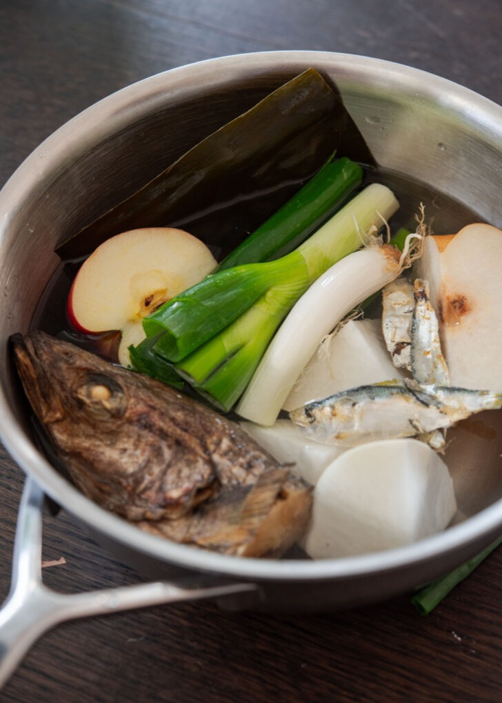 Making kimchi stock with dried fish and other ingredients in a pot.