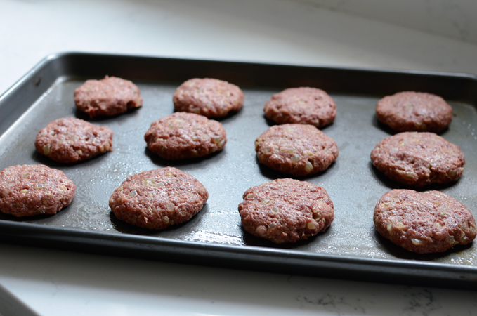 tteokgalbi beef patties flattened on a greased baking sheet.
