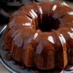 Vegan banana bundt cake with chocolate glaze on a metal plate.