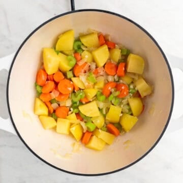 Vegetables sautéed in olive oil in a large pot.
