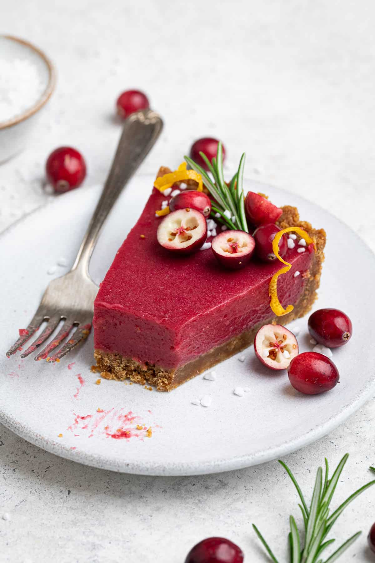 A half eaten slice of vegan cranberry curd tart on a white plate.
