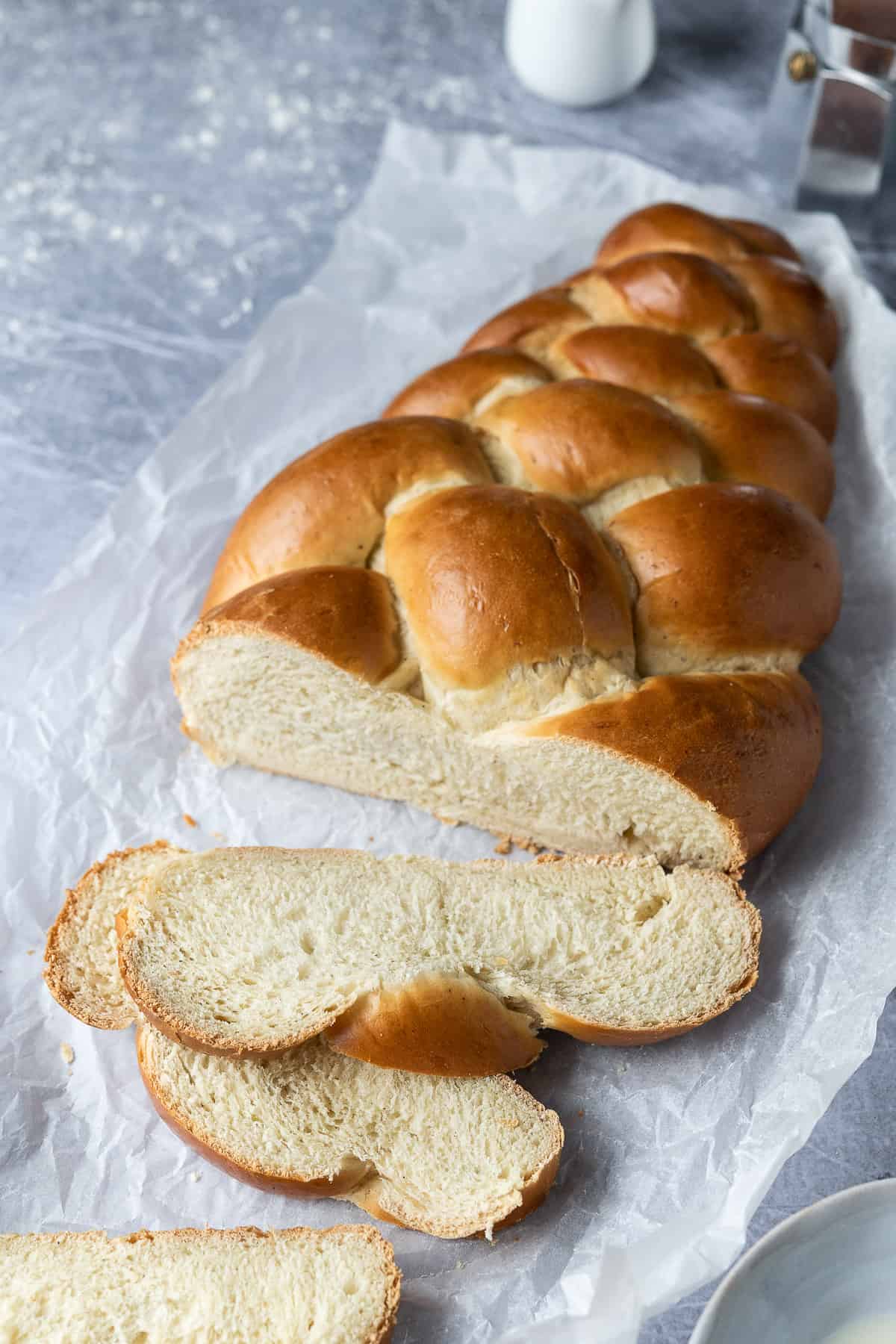 Sliced loaf of bread on white baking parchment on a metal surface.