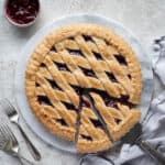 Vegan jam crostata on a marble board with forks and a bowl of jam.