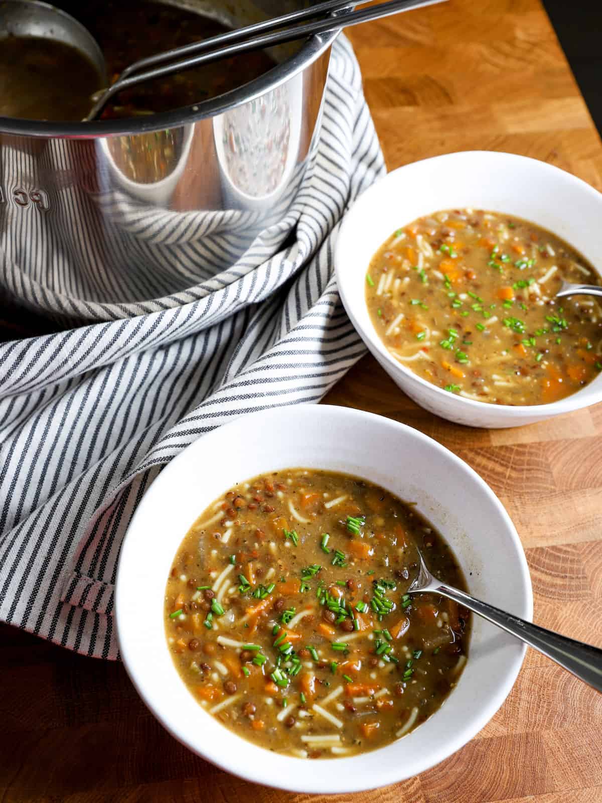Photo showing instant pot in the background and two bowls of soup served in front. 