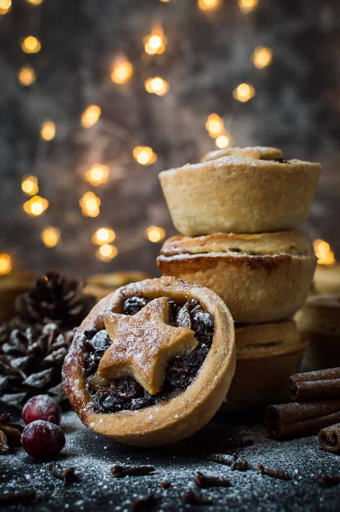 A stack of vegan mince pies with fruit filling and coconut oil pastry in a Christmas scene.
