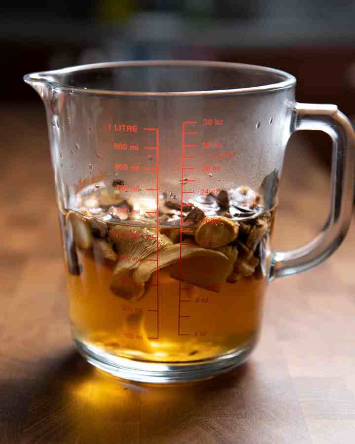 Photo of dried mushrooms re-hydrating in a jug of boiling water.