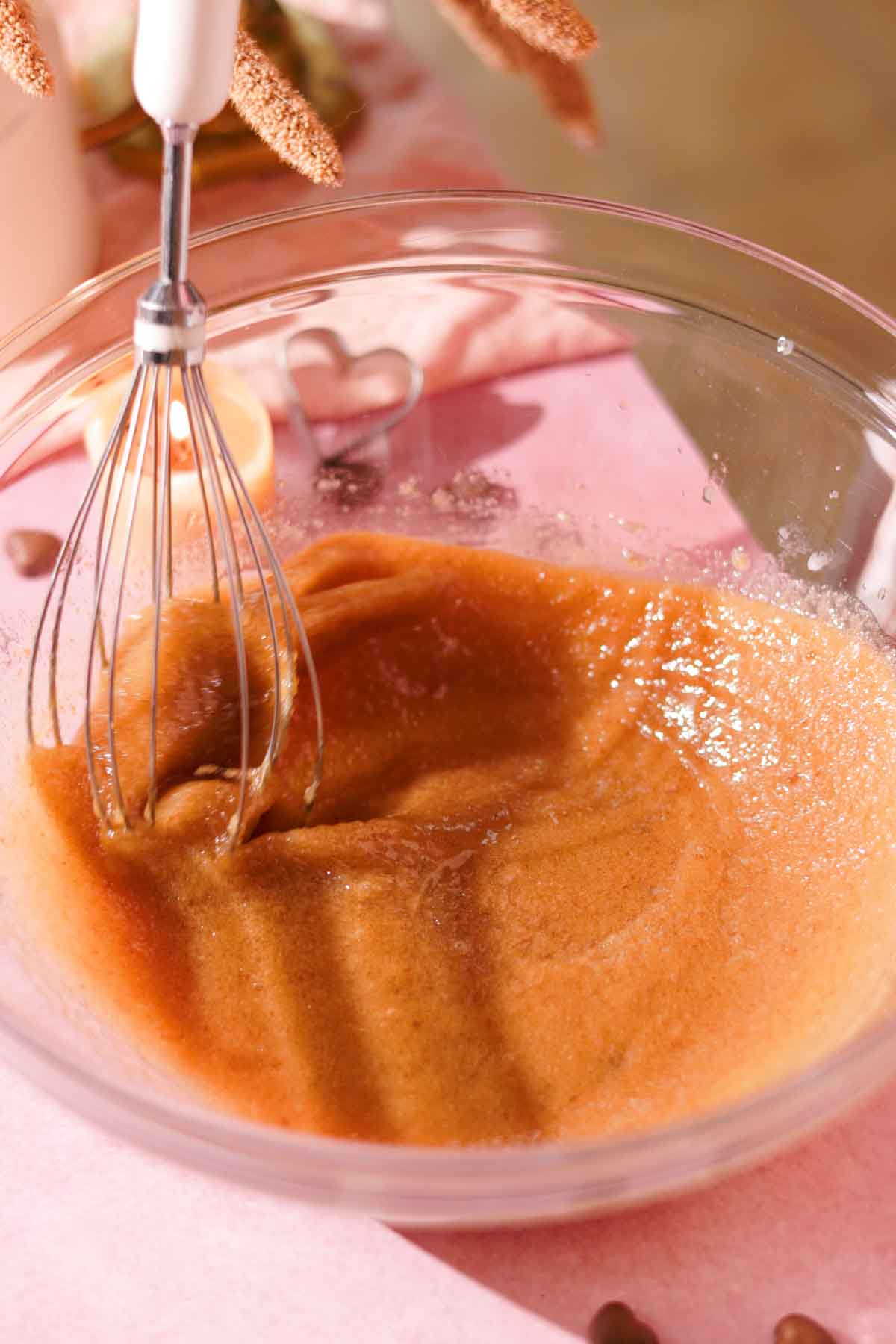 whisking butter and sugar with a wire whisk in a glass bowl