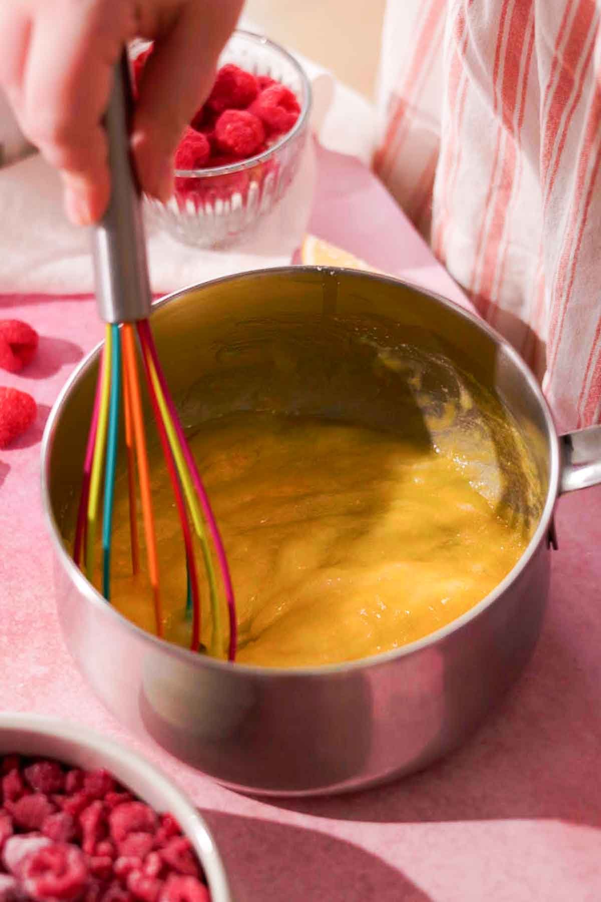 whisking eggs, yolks, and sugar in metal saucepan
