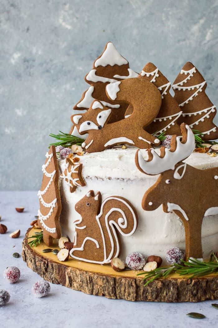 A side shot of vegan woodland animal ginger cake topped with gingerbread fox, squirrel, moose and trees.