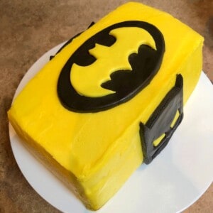 yellow batman cake on a cake stand.