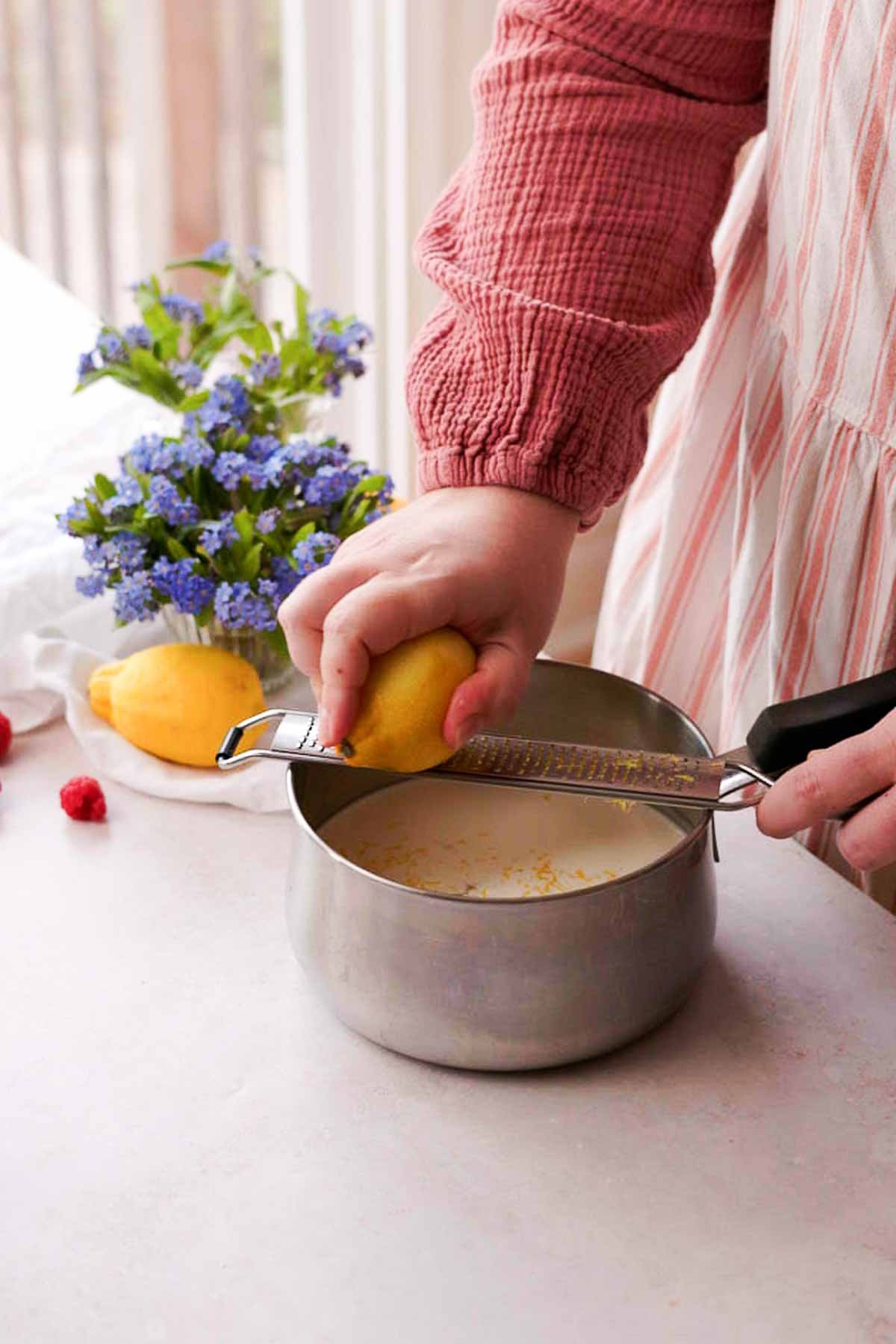 grating lemon zest into saucepan of cream